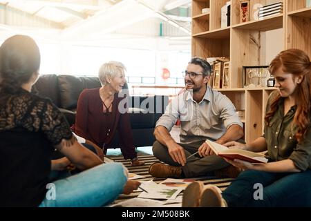 Pensiamo diversamente. un gruppo di uomini d'affari che hanno una sessione di brainstorming mentre sono seduti sul pavimento. Foto Stock