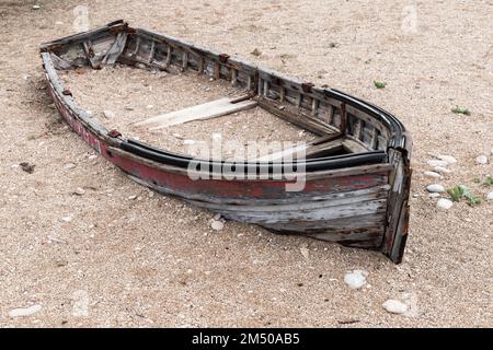 Rotto abbandonato barca di legno giace su una spiaggia di giorno Foto Stock