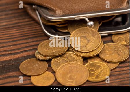 Vecchie monete dell'URSS e un portafoglio vintage in pelle marrone su una superficie di legno. Primo piano, messa a fuoco selettiva. Foto Stock