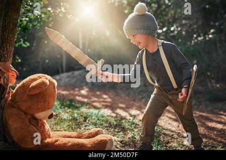 Non abbiate paura - io sconfiggerò questo grande orso spaventoso. un adorabile ragazzino che gioca con una spada di cartone e uno scudo all'esterno. Foto Stock