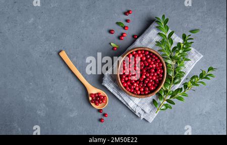 succosa mirtillo rosso in una ciotola di legno con cucchiaio su tavolo grigio scuro. Concetto di cibo sano. Vista dall'alto e immagine dello spazio di copia Foto Stock