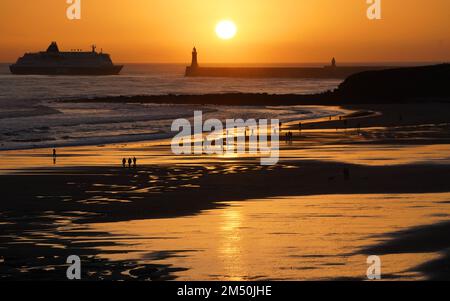 La gente gode di una passeggiata della vigilia di Natale all'alba sulla spiaggia di Tynemouth Longsands nel Nord Est dell'Inghilterra. Data immagine: Sabato 24 dicembre 2022. Foto Stock