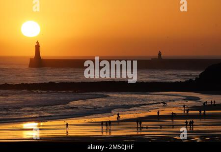 La gente gode di una passeggiata della vigilia di Natale all'alba sulla spiaggia di Tynemouth Longsands nel Nord Est dell'Inghilterra. Data immagine: Sabato 24 dicembre 2022. Foto Stock