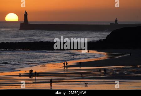 La gente gode di una passeggiata della vigilia di Natale all'alba sulla spiaggia di Tynemouth Longsands nel Nord Est dell'Inghilterra. Data immagine: Sabato 24 dicembre 2022. Foto Stock