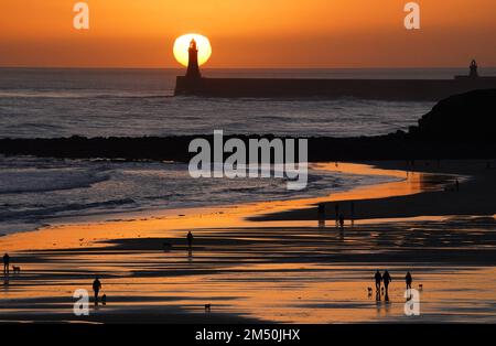 La gente gode di una passeggiata della vigilia di Natale all'alba sulla spiaggia di Tynemouth Longsands nel Nord Est dell'Inghilterra. Data immagine: Sabato 24 dicembre 2022. Foto Stock