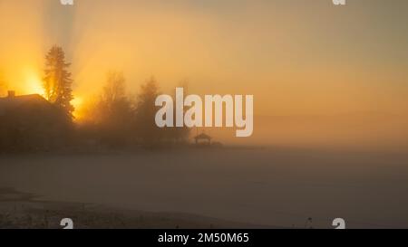 Tramonto sul lago di Bysjön Grangärde in Svezia con nebbia che copre il ghiaccio sul lago Foto Stock