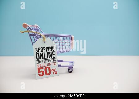 Shopping Online sale 50% messaggio di testo sulla tassa di prezzo con carrello shopping su sfondo blu e rosa Foto Stock
