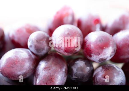 Uve rosse con lieve rugiada sulla superficie dei frutti, primo piano su fondo bianco Foto Stock