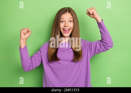 Foto di overjoyed bella signora indossare abiti trendy primavera viola sollevare mani pugno hooray sì isolato su sfondo di colore verde Foto Stock