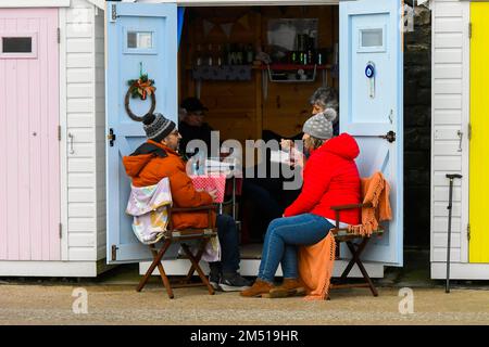 Lyme Regis, Dorset, UK. 24th dicembre 2022. Meteo nel Regno Unito. Le persone che si trovano fuori di una capanna sul lungomare a Lyme Regis in Dorset come godere di un caldo, giornata di festa la vigilia di Natale. Picture Credit: Graham Hunt/Alamy Live News Foto Stock