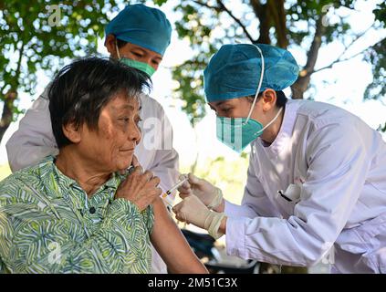 Wenchang, la provincia cinese di Hainan. 22nd Dec, 2022. Un operatore sanitario somministra una dose di vaccino COVID-19 ad un anziano residente nel villaggio Hufeng di Wenchang, nella provincia Hainan della Cina meridionale, il 22 dicembre 2022. I servizi porta a porta sono stati offerti per aiutare gli anziani ad ottenere vaccinazioni COVID-19 nella città di Wenchang. Credit: Pu Xiaoxu/Xinhua/Alamy Live News Foto Stock