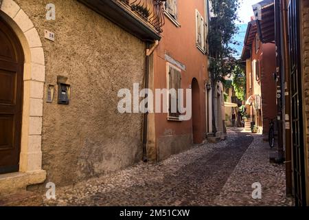 Stretta strada acciottolata che conduce ad un passaggio coperto in un vecchio villaggio Foto Stock