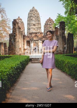 Donna vestita viola e vecchio tempio a Sukhothai, Thailandia nel marzo 13 2021 Foto Stock