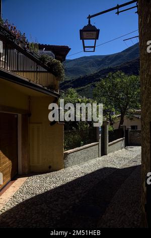 Stretta strada acciottolata che conduce ad un passaggio coperto in un vecchio villaggio Foto Stock