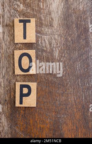 La parola top scritta in piccoli blocchi di legno su uno sfondo rustico. Spazio libero per scrivere. Foto Stock