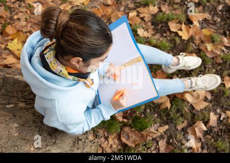 Lo studente siede sotto un albero e scrive su un pezzo di carta, Austria, Salisburgo Foto Stock