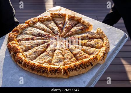 Un'immagine di scorta di una grande pizza affettata servita in un buffet all'aperto. Foto Stock