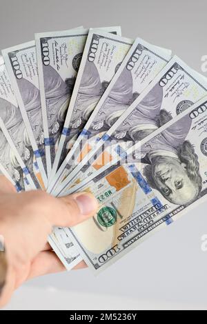 Mano che tiene cento fatture del dollaro su uno sfondo bianco. Foto Stock