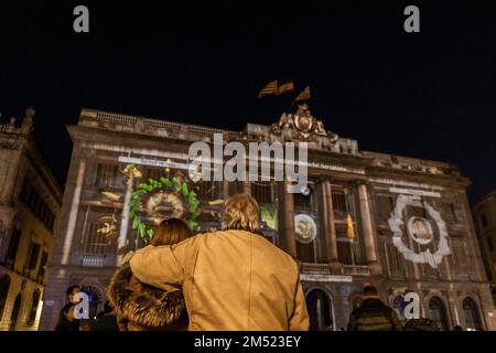 Barcellona, Spagna. 24th Dec, 2022. Una coppia che abbraccia è vista contemplando i presepi digitali proiettati durante la vigilia di Natale 2022. Il Consiglio comunale di Barcellona, guidato dal sindaco Ada Colau, ha realizzato una "mappatura video" proiettata sulla facciata del Municipio in Plaza de Sant Jaume che rappresenta varie scene natalizie tradizionali in Catalogna. (Foto di Paco Freire/SOPA Images/Sipa USA) Credit: Sipa USA/Alamy Live News Foto Stock