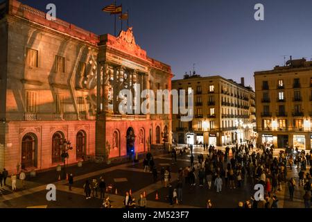 Barcellona, Spagna. 24th Dec, 2022. Un grande gruppo di persone che contemplano i presepi digitali durante la vigilia di Natale 2022. Il Consiglio comunale di Barcellona, guidato dal sindaco Ada Colau, ha realizzato una "mappatura video" proiettata sulla facciata del Municipio in Plaza de Sant Jaume che rappresenta varie scene natalizie tradizionali in Catalogna. (Foto di Paco Freire/SOPA Images/Sipa USA) Credit: Sipa USA/Alamy Live News Foto Stock