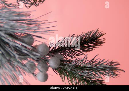 foto parte artificiale di un ramo di abete rosso su sfondo rosa Foto Stock