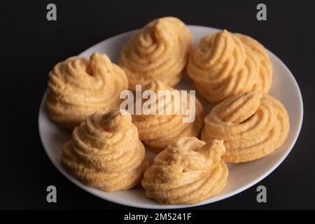 foto di diverse meringhe a spirale giacenti su un piatto in primo piano su uno sfondo nero Foto Stock