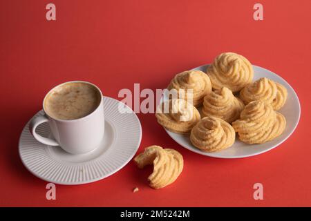 fotografare la torta di meringa su un piatto bianco e una tazza di caffè su sfondo rosso Foto Stock