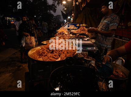 Tehatta, Bengala Occidentale, India. 23rd Dec, 2022. Jalebi è uno snack dolce molto popolare in Asia meridionale e occidentale, Africa e Mauritius. Va da molti nomi, compreso jilapi, zelepi, jilebi, jilipi, zulbia, jerry, mushabak, z'labia, o zalabia. La varietà dell'Asia meridionale è prodotta friggendo a fondo la farina di maida (farina semplice o farina universale) in pastella pretzel o forme circolari, che vengono poi imbevute in sciroppo di zucchero. Jalebi è mangiato con cagliata o rabbri (in India del Nord) insieme ad altri sapori facoltativi come kewra (acqua profumata). Questa foto è stata scattata in una fiera del villaggio dove si trovavano i caldi Jalebi-s. Foto Stock