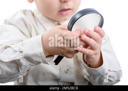 Baby in possesso di una lente di ingrandimento in mano su uno sfondo bianco Foto Stock