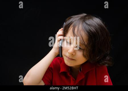 Little Boy tenere lo smartphone come moderna comunicazione mobile gadget Foto Stock