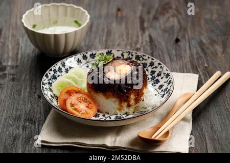 Nasi Tim Ayam, cucina indonesiana con influenza cinese popolare per colazione. Cuocere a vapore il riso con pollo condito e uovo salato. Foto Stock