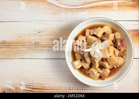 Tofu Mapo, tofu cubito in salsa piccante. Vista dall'alto su tavolo in legno Foto Stock