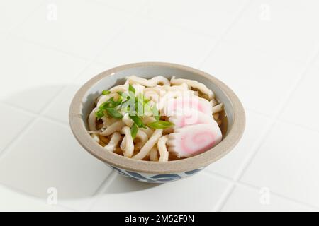 Giapponese Kake Udon Noodles in una ciotola con kamaboko su sfondo bianco, Copy Space Foto Stock