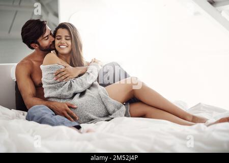 Avvolti tra le braccia, avvolti nel tuo amore. una giovane coppia affettuosa in camera da letto a casa. Foto Stock