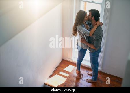 Tu vuoi dire il mondo per me. una giovane coppia affettuosa che condivide un bacio a casa. Foto Stock