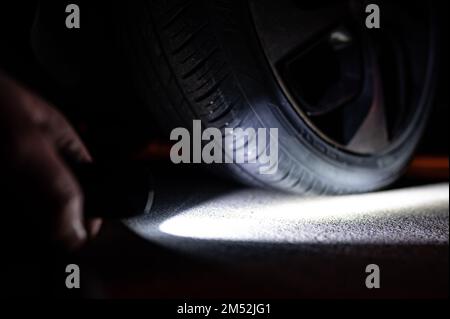 Torcia rivolta verso uno pneumatico sgonfio durante la notte Foto Stock