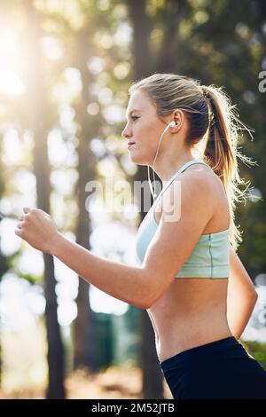 Ecco qui. una giovane donna che fa jogging fuori nella foresta. Foto Stock