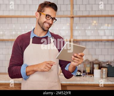I miei clienti scrivono i commenti più belli. un giovane e felice imprenditore che utilizza un tablet mentre si trova nella sua caffetteria. Foto Stock
