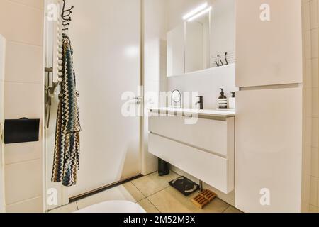 un bagno con wc, specchio e asciugamano appesi alla parete dietro è una porta bianca che conduce ad una doccia aperta Foto Stock