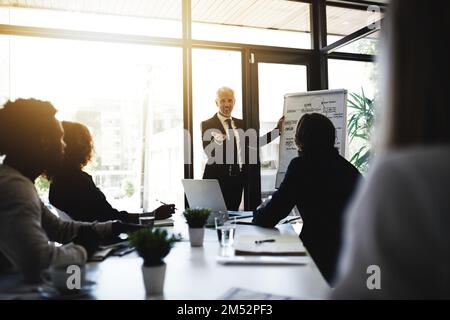 Parlare nuove strategie con il suo team. un uomo d'affari maturo che offre una presentazione ai colleghi in una sala riunioni. Foto Stock