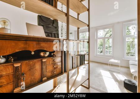 un gatto che posa sopra un armadietto di legno in un soggiorno con pareti bianche e rivestimenti di legno intorno ad esso Foto Stock