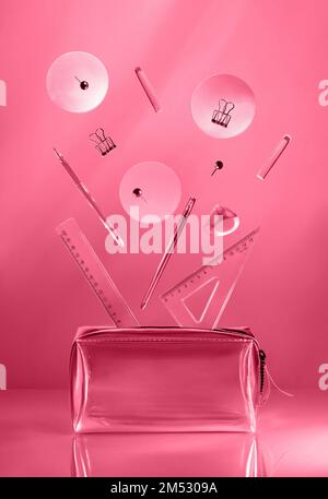 Composizione creativa realizzata con forniture scolastiche che volano in aria su sfondo nero isolato con spazio copia. Immagine colorata in color magenta trendy dell'anno 2023. Ritorno a scuola. Foto Stock