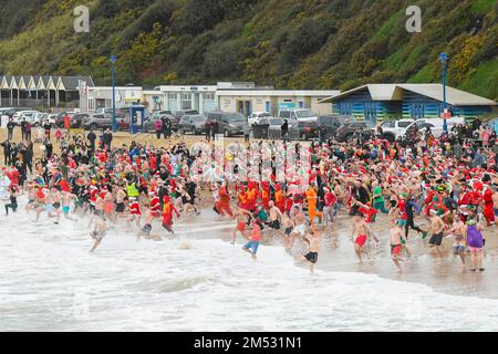 Boscombe, Dorset, Regno Unito. 25th dicembre 2022. Meteo nel Regno Unito. Centinaia di festaioli del giorno di Natale che indossano abiti eleganti e festosi si tuffano nel mare freddo a Boscombe a Bournemouth in Dorset per il bagno di beneficenza Macmillan White Christmas DIP nuotare in una fredda mattinata. Picture Credit: Graham Hunt/Alamy Live News Foto Stock