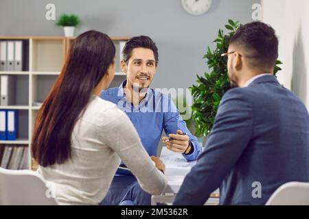 Felice coppia di famiglia che firma il contratto insieme in ufficio Foto Stock