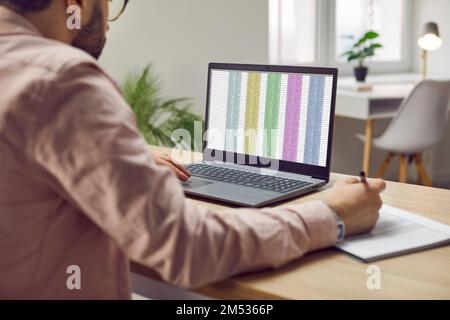 Uomo d'affari o contabile finanziario che lavora in ufficio e utilizzando schede tecniche sul computer portatile Foto Stock