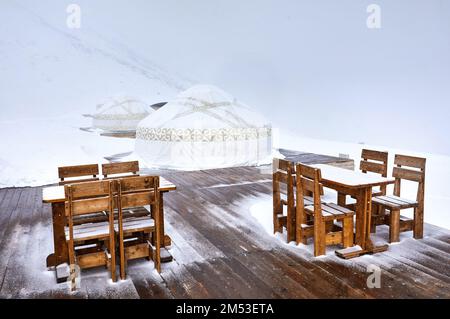 Hotel e Ristorante dal complesso di casa nomade di Yurt e tavolo con sedia presso la stazione sciistica di Shymbulak ad Almaty, Kazakhstan. Inverno nevicate outdoor touri Foto Stock