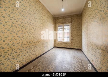 Camera da letto con pareti coperte di vecchia carta da parati sporca, pavimento in gres idraulico usurato e sporche finestre di legno dipinte di bianco Foto Stock