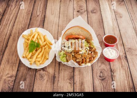 Tipico sandwich di carne di agnello kebab alla griglia su spiedino servito come menu con patatine fritte, salse di pomodoro e yogurt in un ristorante europeo Foto Stock