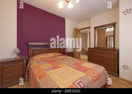 Camera da letto con pareti bicolore, letto matrimoniale con testiera in legno e comodini e cassettiera con specchio coordinato Foto Stock