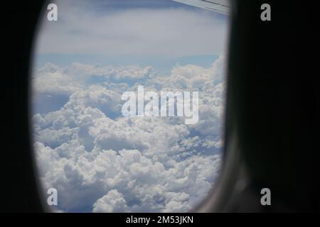 Vista dalla finestra di un aereo commerciale, nuvole soffici visibili sullo sfondo Foto Stock